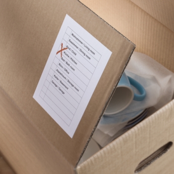 Étiquette HERMA blanche sur un carton de déménagement.