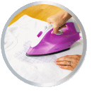 Une main tient un fer à repasser violet, utilisé sur un morceau de tissu blanc pour lisser les plis.