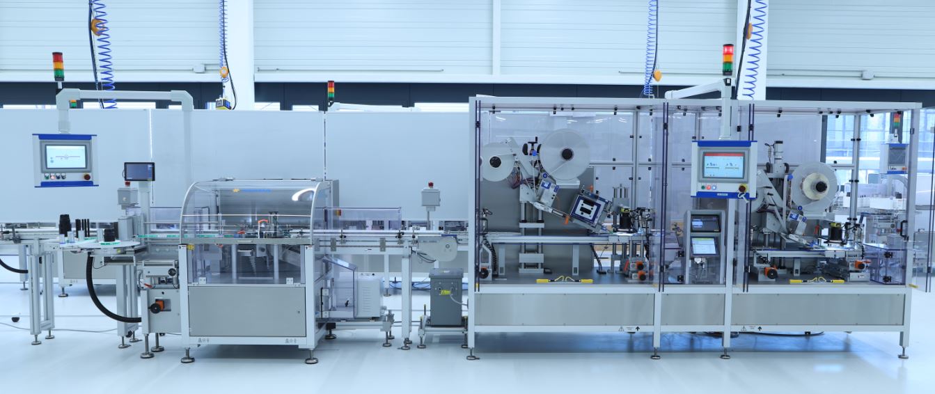  ligne de production automatisée avec plusieurs machines, écrans et dispositifs de sécurité dans un environnement industriel moderne.
