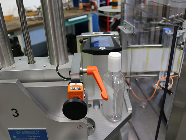 Une machine de remplissage avec un réservoir transparent et un levier orange, prête à être remplie.