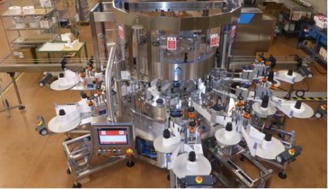 Machine d'étiquetage automatique à plusieurs stations, équipée d'un panneau de commande et de nombreux bras d'étiquetage.