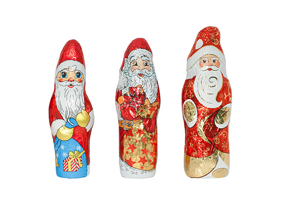 Trois décoratifs pères Noël en chocolat, chacun dans des designs et des couleurs différentes, se tiennent côte à côte.