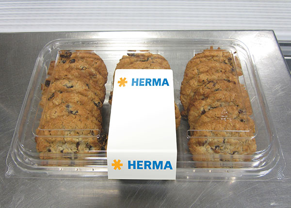 Un emballage contenant plusieurs biscuits au chocolat, séparés par une étiquette portant l'inscription 'HERMA' au centre.