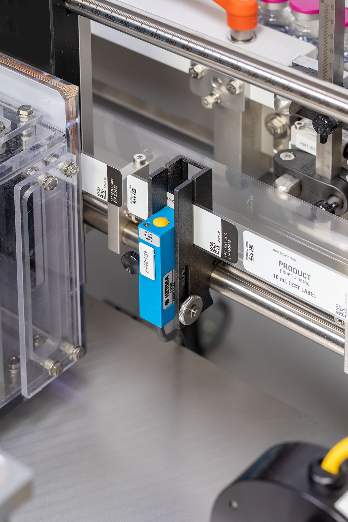 Un appareil d'étiquetage avec un capteur bleu qui reconnaît les étiquettes sur des emballages transparents. Plusieurs étiquettes sont visibles.