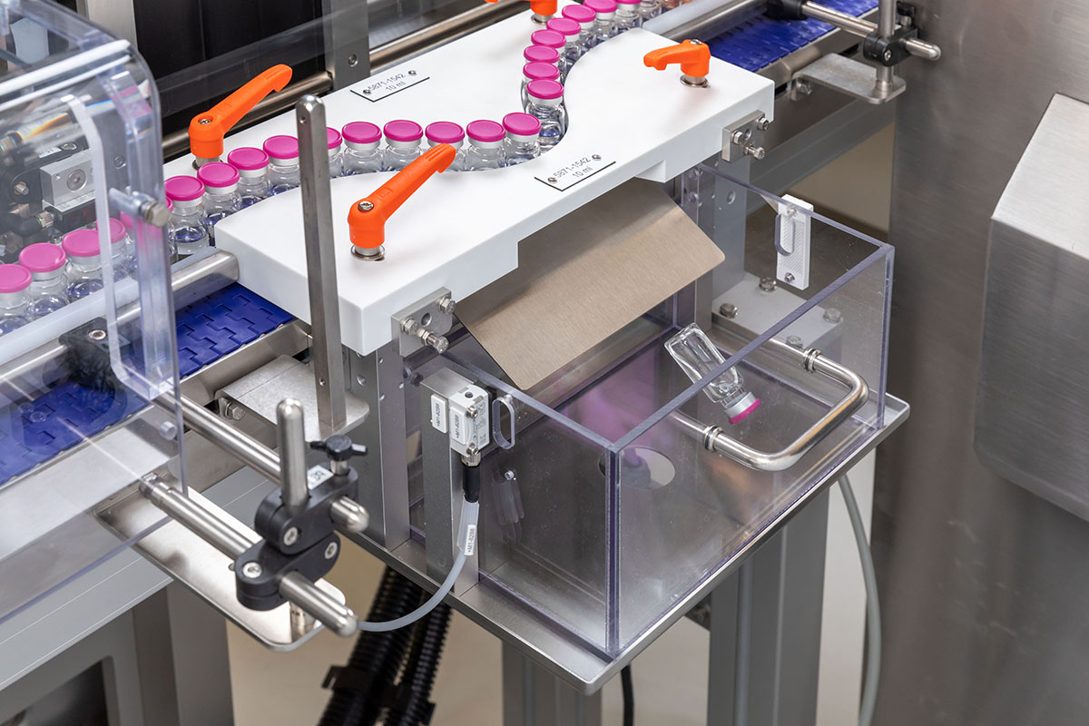 Installation de remplissage automatisée avec des bouteilles sur un convoyeur et un conteneur pour le stockage des matériaux d'emballage.