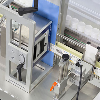 Texte : "Machine d'emballage de produits, équipée de divers composants mécaniques et de contrôles.