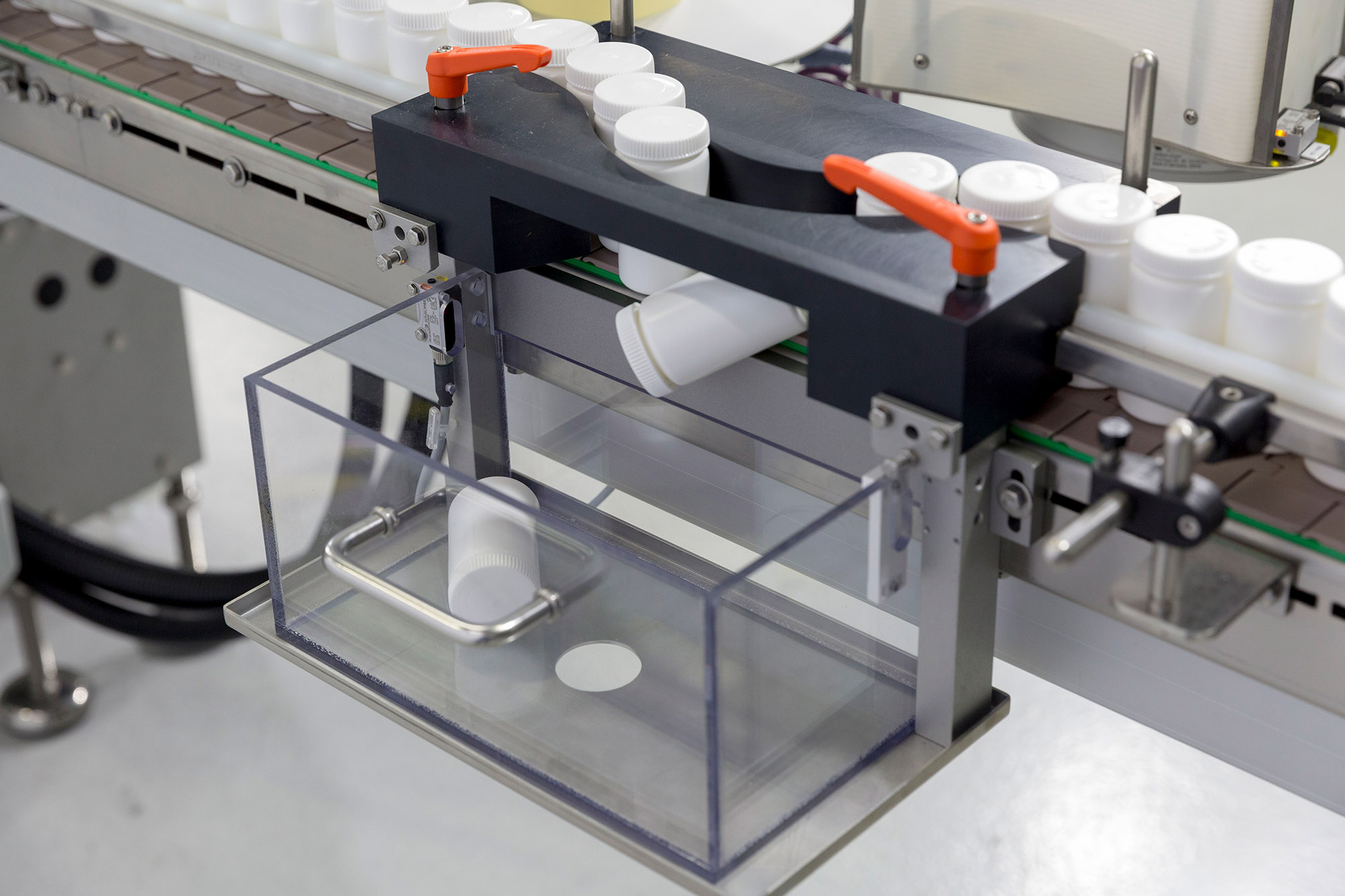 Machine d'emballage automatisée avec un conteneur transparent qui reçoit le conteneur d'un tapis roulant.