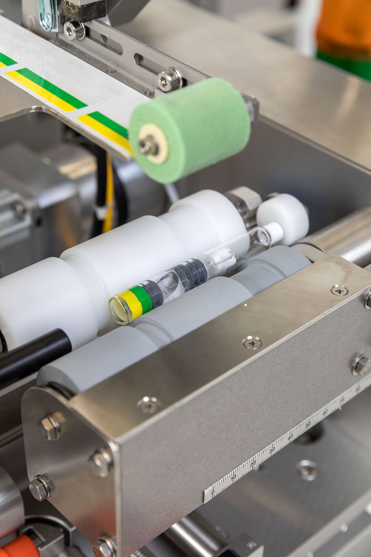 Des pièces de machine avec des tubes transparents et une roue en caoutchouc verte, disposées dans un environnement industriel.