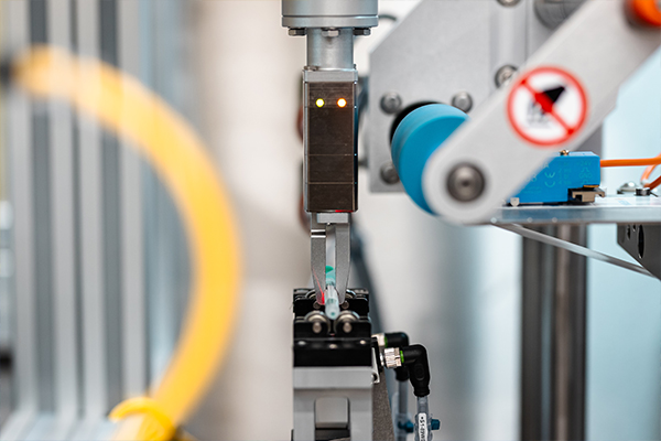 Un bras robotisé automatisé avec une pince qui effectue un mouvement précis pour saisir un objet.