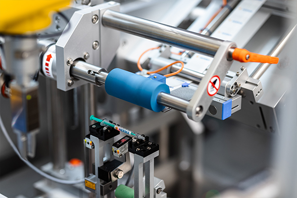 Composants de machines automatisées avec un cylindre bleu et différents pinces pour la manipulation d'objets dans un environnement industriel.