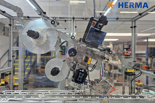 Machine étiqueteuse automatisée avec rouleaux et unité de contrôle dans un environnement de production.