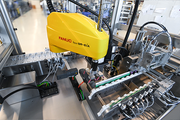 Robots industriels de FANUC, modèle R-6iA, dans un environnement de fabrication automatisé, avec divers composants pour l'assemblage.