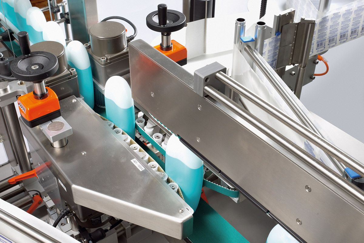 Une ligne de production avec des bouteilles transportées sur un tapis roulant. Des composants de machines sont visibles, soutenant le processus de remplissage.