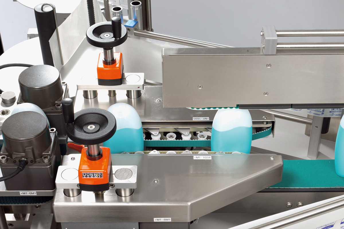 Machines de remplissage de liquides, avec des bouteilles de couleur bleue et blanche sur un tapis roulant.