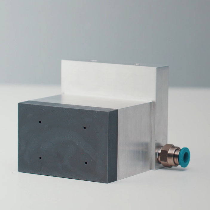 Un appareil rectangulaire avec une surface métallique et un bloc en plastique noir, équipé d'une connexion.