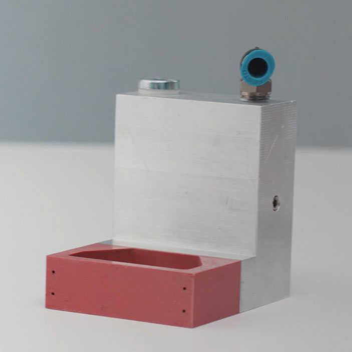 Composant en aluminium avec élément en plastique rouge et raccord pour air comprimé. Idéal pour des applications industrielles.