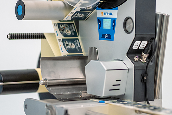 Machine à étiqueter avec écran numérique et bande d'étiquettes en cours. La machine est conçue pour l'étiquetage des produits.