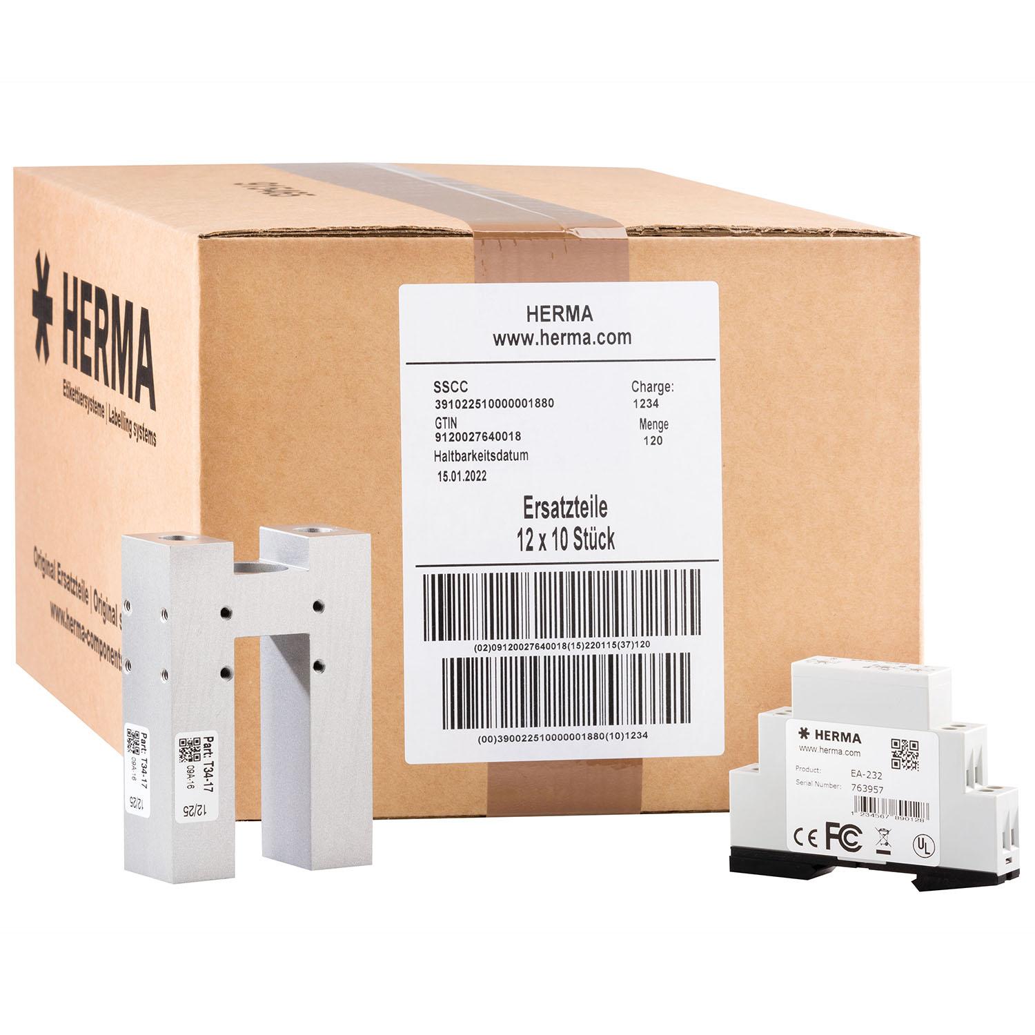 Carton avec des pièces de rechange de HERMA, y compris deux pièces en aluminium et plusieurs composants plus petits.