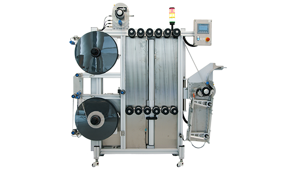 Une machine d'emballage industrielle avec deux grands rouleaux, une unité de contrôle et une zone de sortie pour les produits emballés.