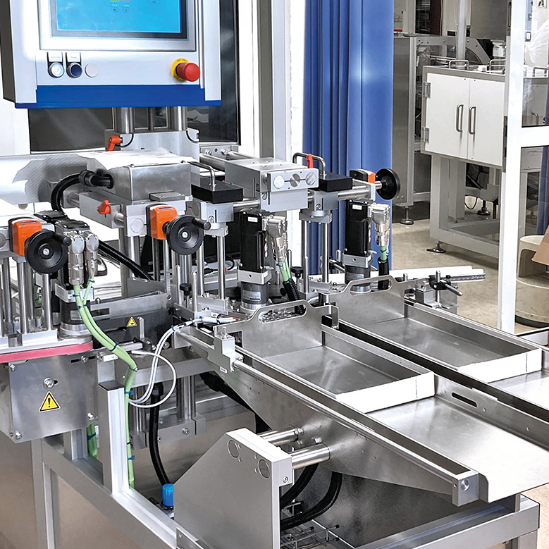 Agencement automatisé de machines avec plusieurs bras de préhension et unité de contrôle, conçu pour les processus de fabrication industrielle.