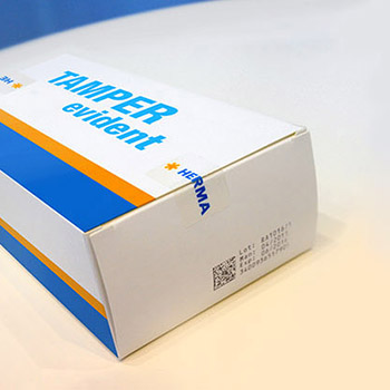 Emballage avec l'impression "TAMPER evident" et le logo de HERMA, indiquant une sécurité contre la manipulation.