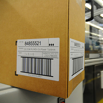 Étiquettes activables au laser : étiquette d'expédition sur carton brun dans la logistique.