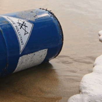 Fût de chimie échoué sur la rive, avec une étiquette résistante à l'eau de mer.