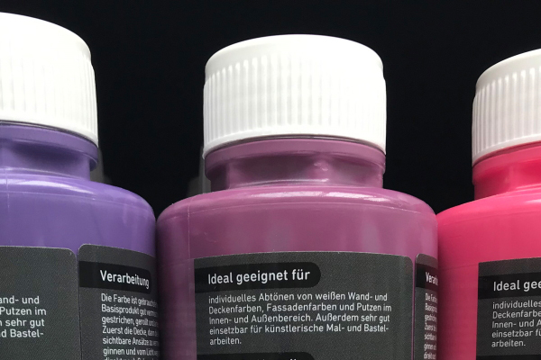 Solutions secteur des matériaux de construction : étiquettes en impression numérique sur des bouteilles colorées dans les rayons des magasins de bricolage, détail au dos.
