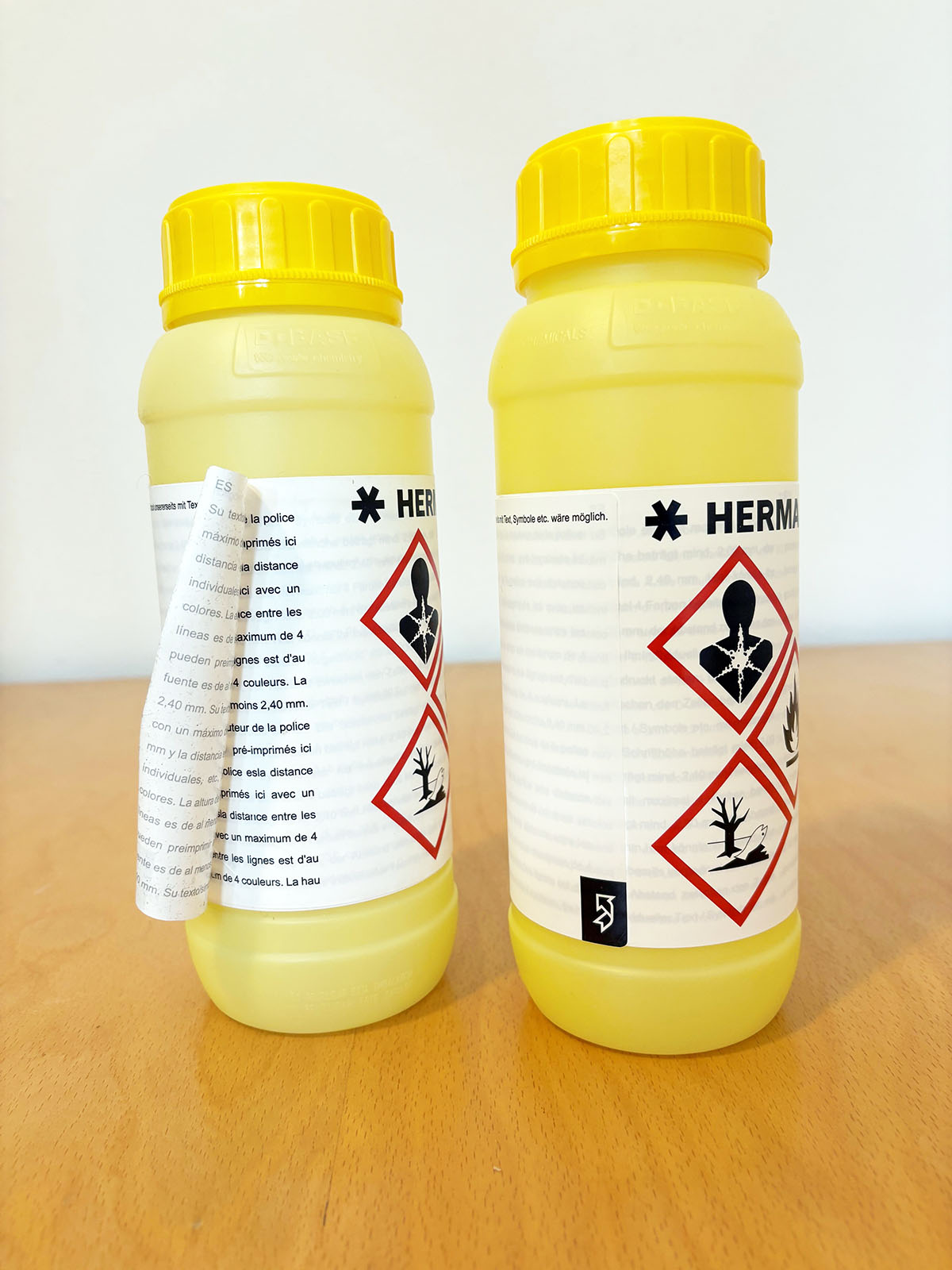 Deux bouteilles jaunes avec des avertissements et des symboles de danger, contenant des substances chimiques. Les étiquettes informent sur les mesures de sécurité.