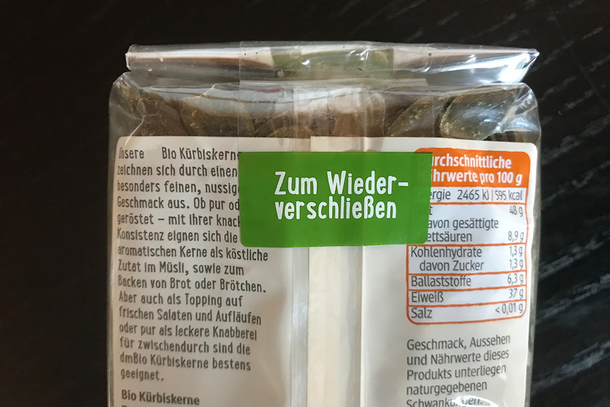 Étiquettes de fermeture : étiquette de fermeture transparente avec languette colorée imprimée, sur un emballage en sachet contenant des graines de courge.