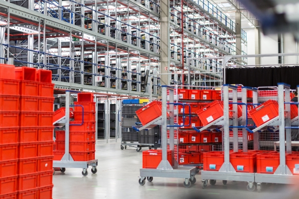 Stockage de petites pièces avec des étiquettes sur des caisses de transport rouges.