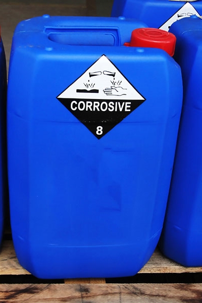 Étiquettes de substances dangereuses et de marchandises dangereuses : Étiquettes de marchandises dangereuses sur des bidons en plastique bleus dans le secteur chimique.