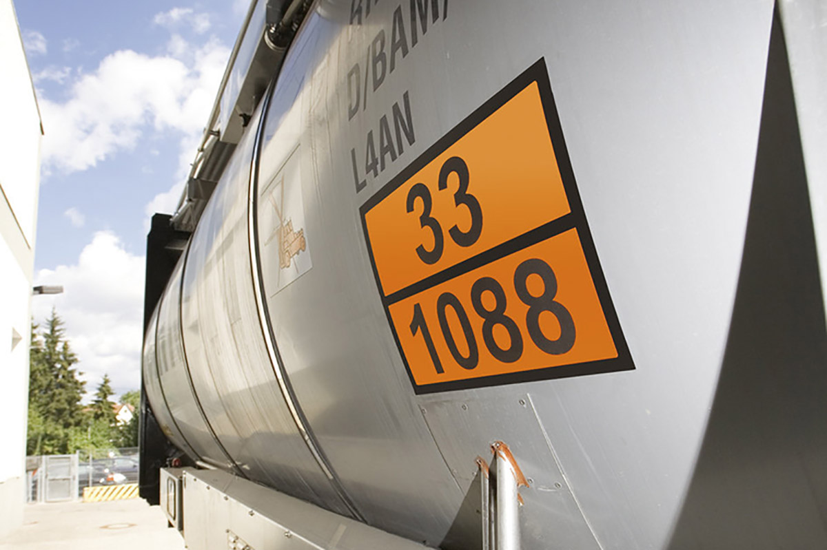 Étiquettes de substances dangereuses et de marchandises dangereuses : panneau orange avec numéros d'identification sur un camion-citerne argenté.