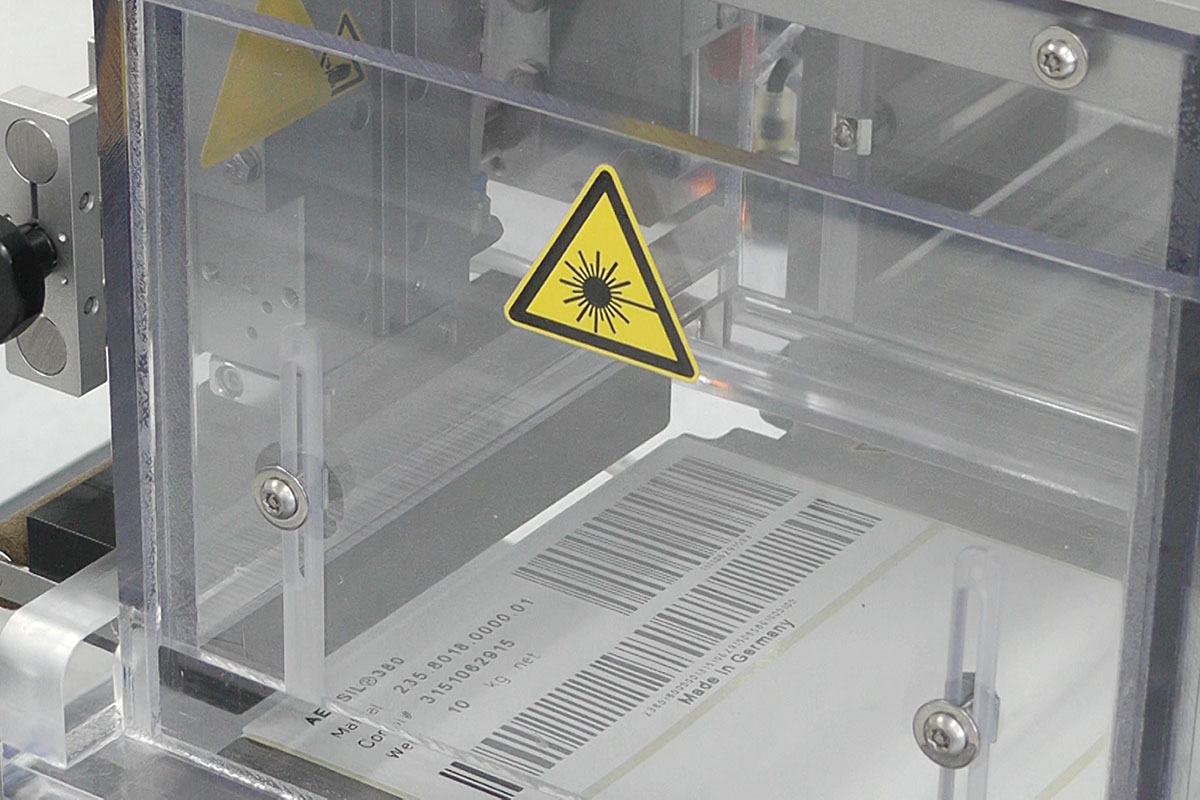 Étiquettes activables au laser : avec code-barres dans le processus de production, gros plan de l'unité d'impression laser CO2.