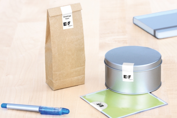 Étiquettes de fermeture : Étiquettes blanches sur un sac en papier brun, une boîte en métal et un sachet en plastique.