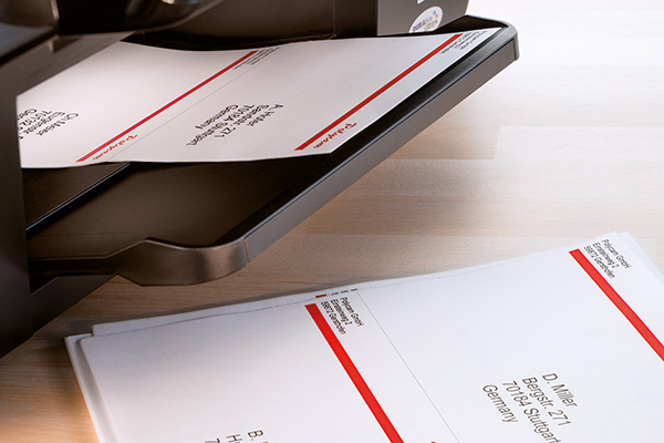 Une feuille d'étiquettes imprimées sort de l'imprimante, utilisée pour des instructions de traitement.