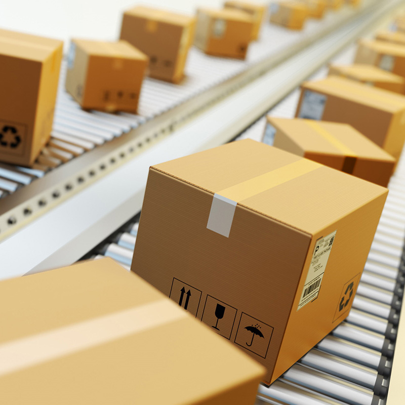 Étiquettes d'expédition et d palettes : étiquette d'expédition sur des cartons bruns, sur un tapis roulant dans la logistique, vue de face.