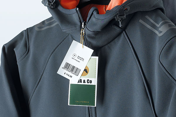Étiquettes suspendues imprimées en couleur avec indication de prix et de produit, sur une veste softshell grise.
