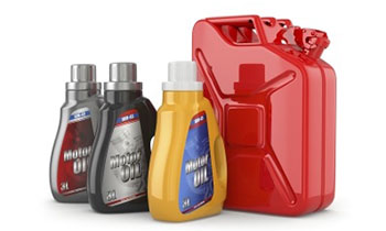Différentes bouteilles d'huile moteur de couleurs variées, à côté d'un jerrycan rouge pour les carburants.
