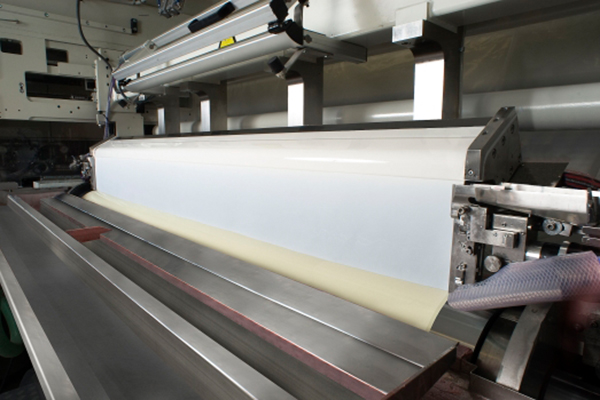 Une machine industrielle qui traite une longue bande de pâte, en mettant l'accent sur le processus de production.