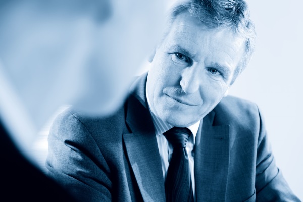 Un homme en costume regarde attentivement et pensivement son interlocuteur.