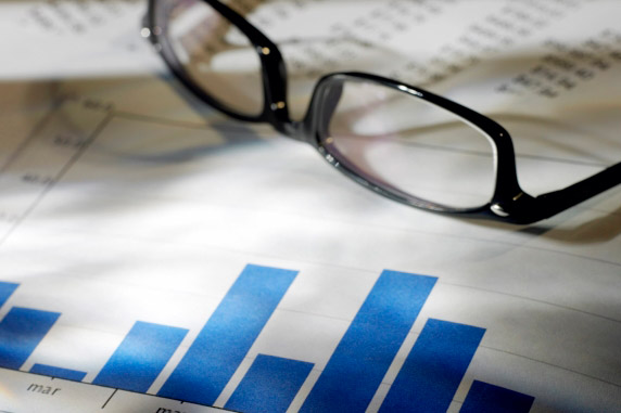 Des diagrammes à barres bleues sur un document, à côté se trouvent des lunettes et d'autres données imprimées.