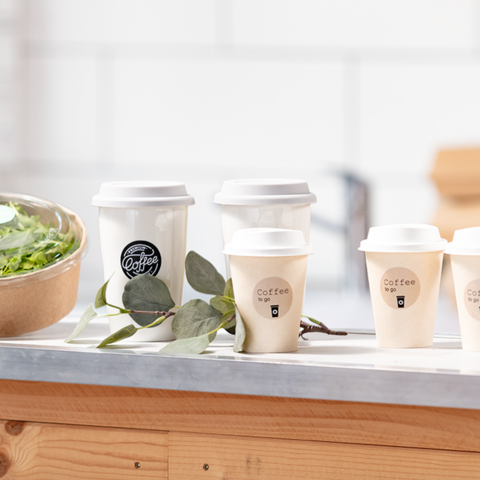 Plusieurs tasses à café sont posées sur une table, à côté d'un saladier avec de la salade et des feuilles vertes.