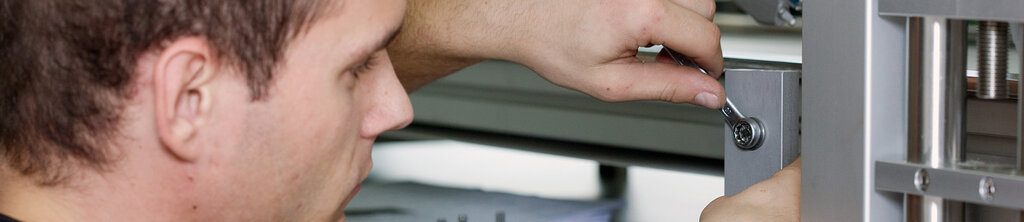 Un homme serre une vis sur un cadre en métal avec une clé à molette.