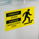 Warnschild mit den Aufschriften "Vorsicht Stufe", "Caution" und "Watch Your Step", das auf eine Treppenstufe hinweist.