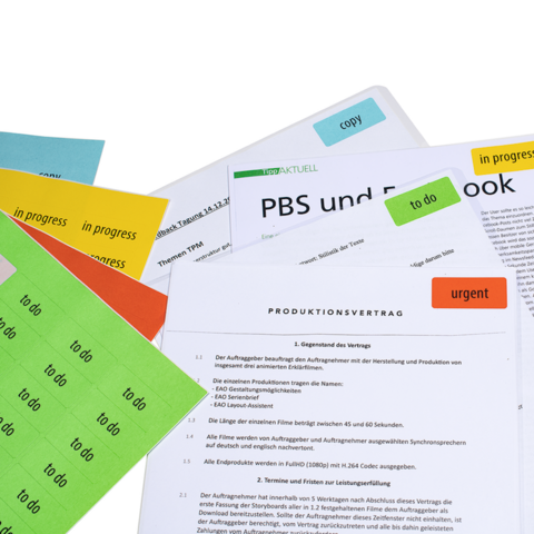 Plusieurs documents avec des post-it de différentes couleurs, y compris un contrat de production et des notes sur des sujets tels que PBS et Facebook.