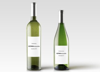 Deux bouteilles de vin blanc avec des étiquettes : un Chardonnay de 2016 et un Riesling de 2017, tous deux portant le nom "HERMAexquisite".