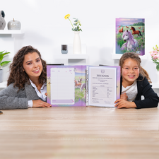 Deux filles sont assises à une table, tenant un cahier ouvert avec un certificat et une feuille blanche. En arrière-plan, des éléments décoratifs sont visibles.