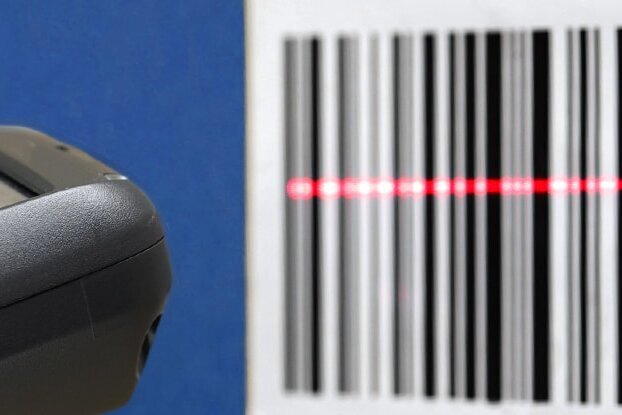 Main avec un scanner en train de scanner une étiquette code-barres, format paysage.