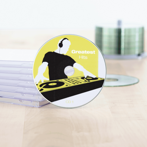 CD mit dem Titel "Greatest Hits", abgebildet mit einem DJ-Design auf gelbem Hintergrund, neben einer Reihe von leeren CD-Hüllen.